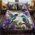 Amethyst Hummingbird Love quilted 3-piece bedding set on a made bed with two matching pillow shams